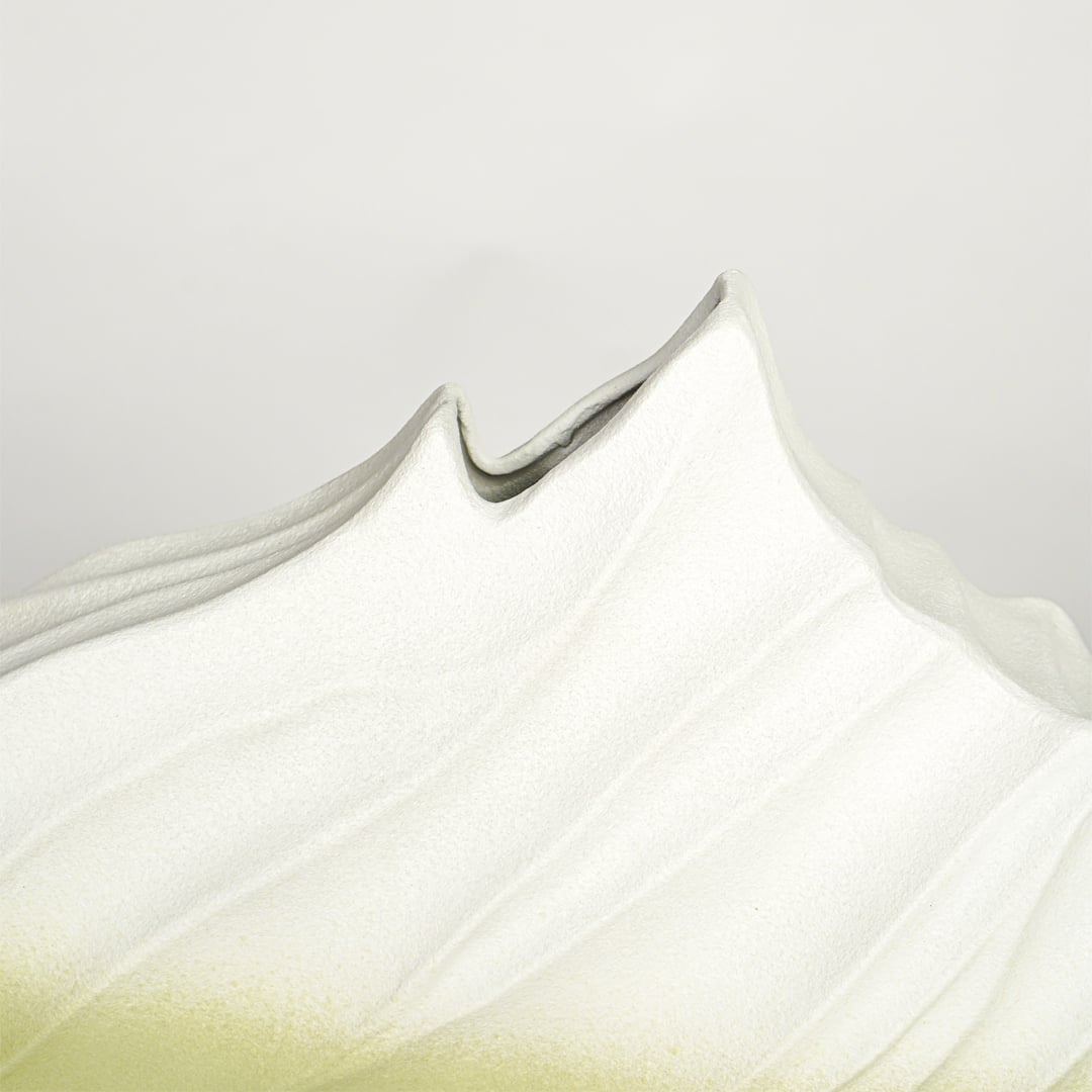 Close up view white and green ceramic vase showing sculpted wave texture matte finish decorative ceramic accent.