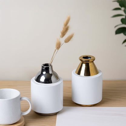 A modern white ceramic vase with a gold metal top displayed on a wooden table styled with minimal decor for an elegant contemporary home setting.