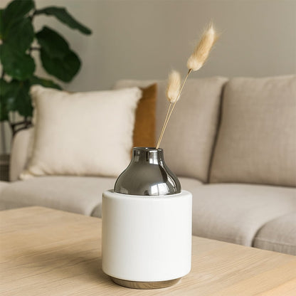 White ceramic decor vase with smoked grey glass neck styled on wooden coffee table adding modern elegance to living room interior.
