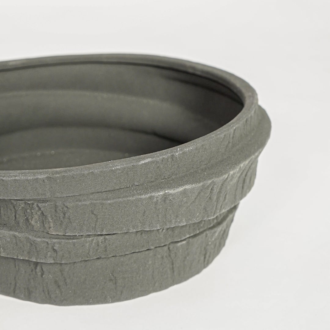 Black ceramic serving bowl with rustic textured stone finish perfect for elegant dining table centerpiece and contemporary home decor styling.