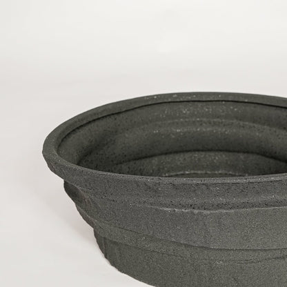 Black ceramic decorative bowl with textured stone surface perfect for elegant dining table centerpiece and interior decor styling.