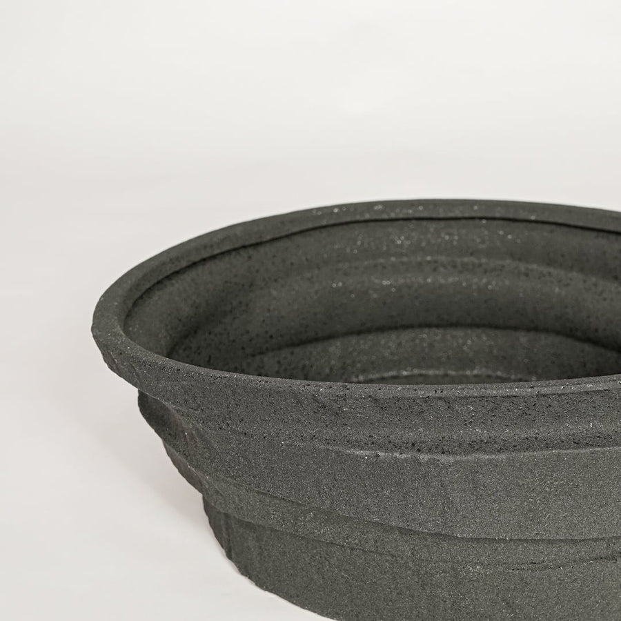 Black ceramic decorative bowl with textured stone surface perfect for elegant dining table centerpiece and interior decor styling.