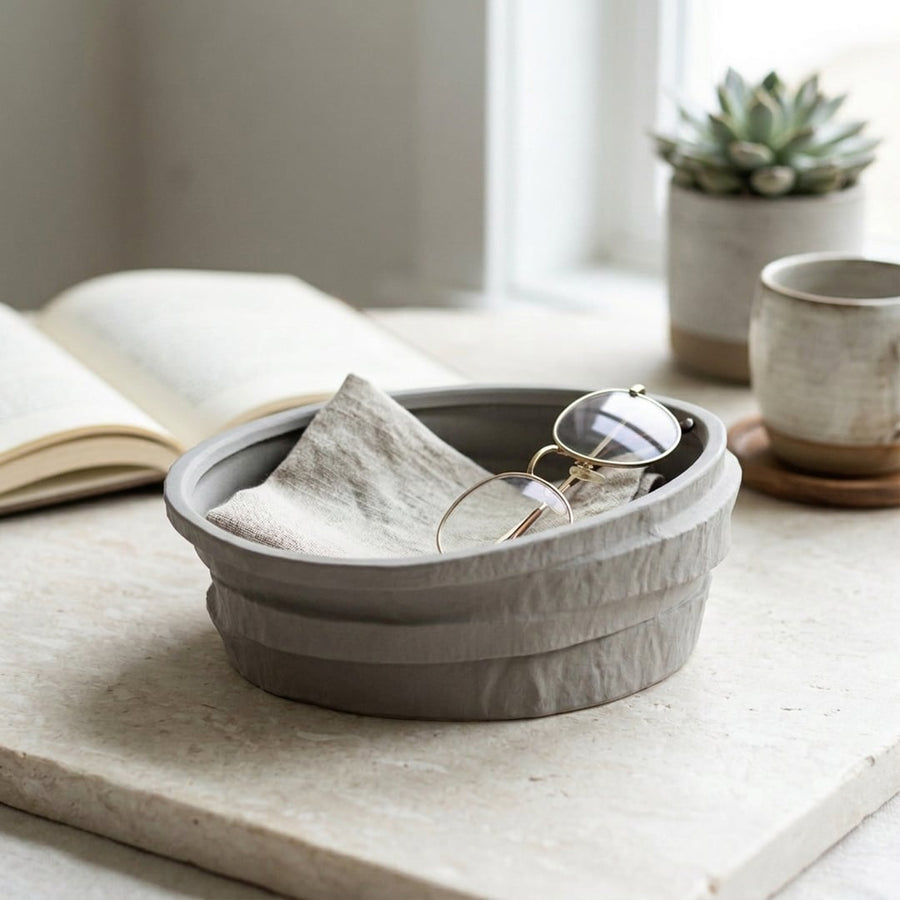 Grey ceramic decorative bowl with textured finish placed on marble table for elegant tabletop decor styling.