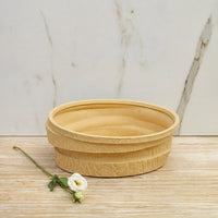 Beige ceramic decorative bowl with layered textured finish placed on wooden table for elegant home decor styling.