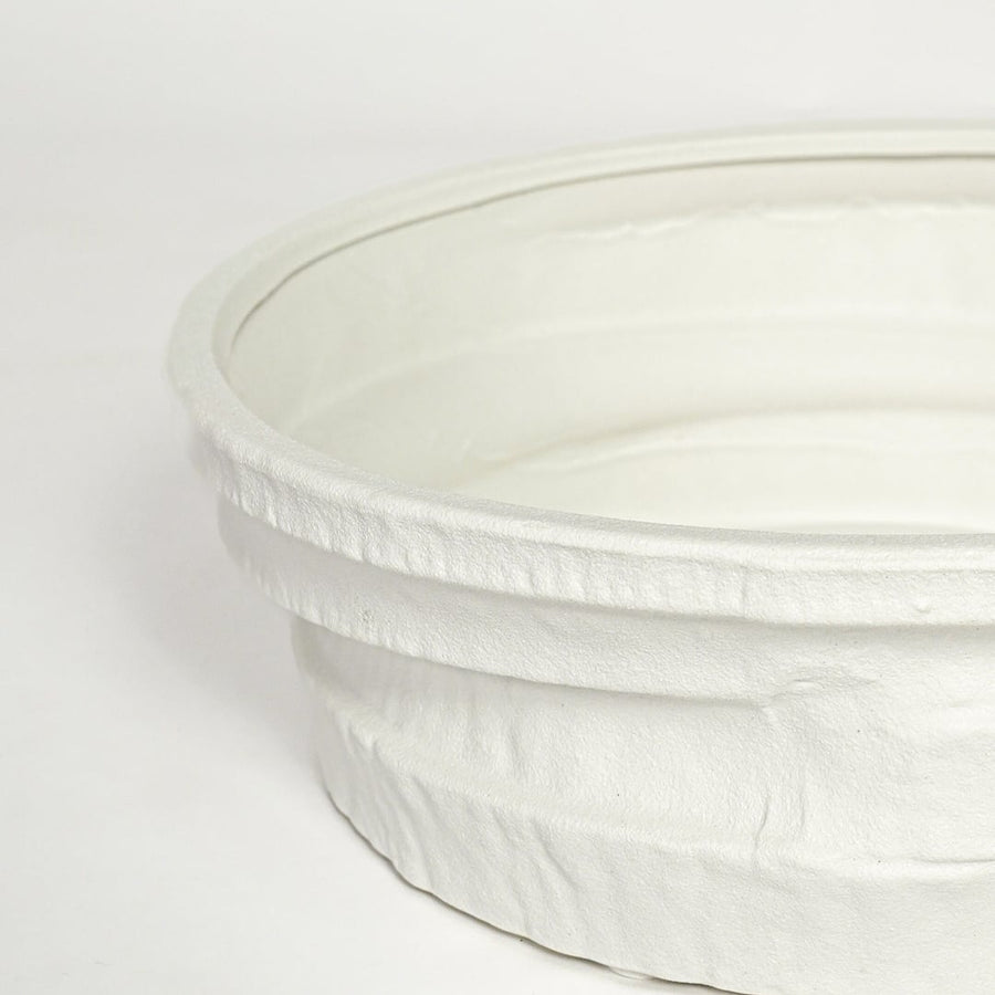 Close view of white ceramic round tray highlighting textured layered rim and smooth matte finish.