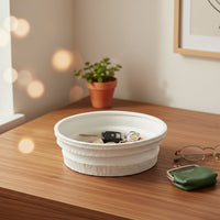 White ceramic round tray placed on wooden table holding accessories adding clean and modern touch to home decor.