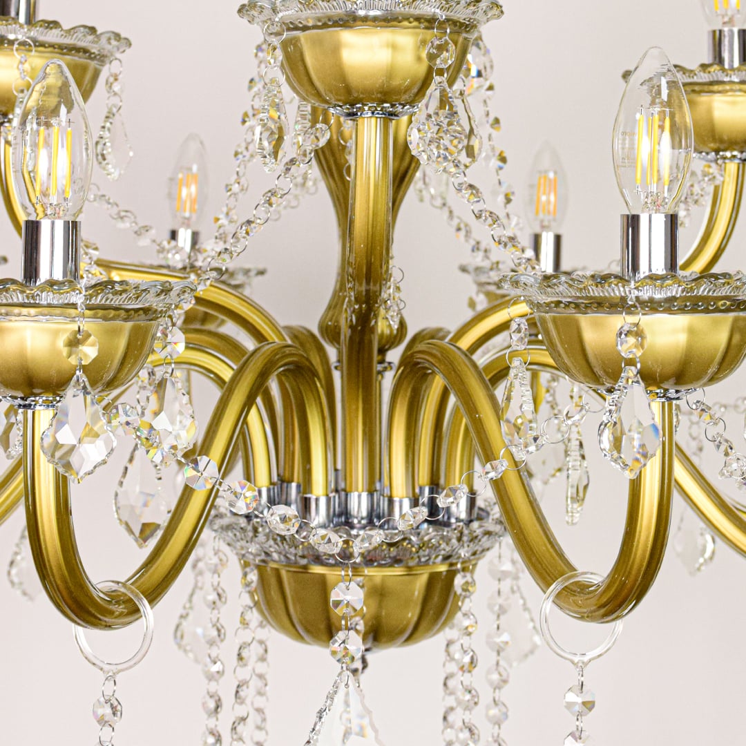 Closeup of gold metal chandelier arms and crystal drops showing fine detailing for premium home lighting.