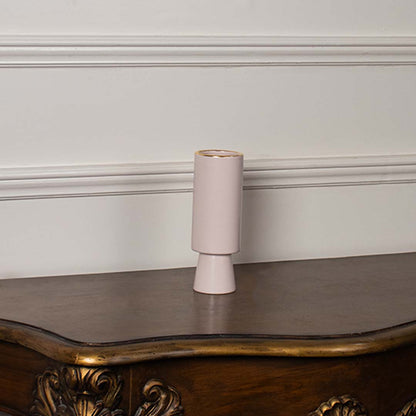 Blush pink ceramic vase placed on a clean white background showing its tall modern cylindrical form with a smooth matte finish and subtle gold rim.