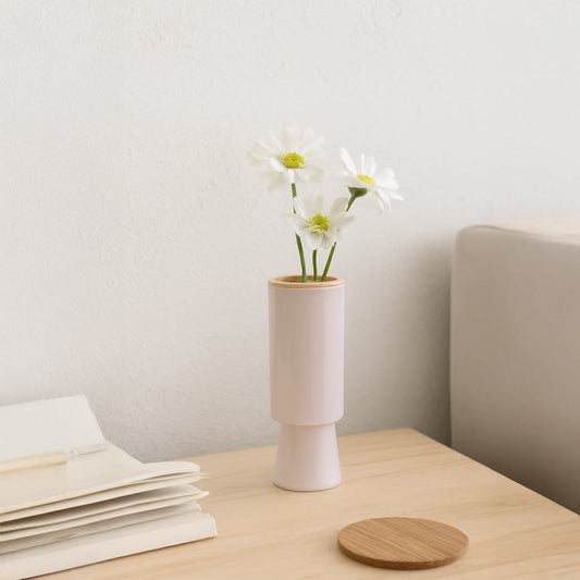 Modern blush ceramic vase displayed in a soft minimal setting showing its tall cylindrical shape and elegant matte finish.