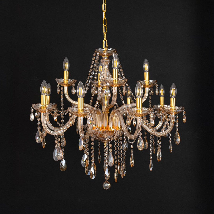 Golden chandelier with crystal droplets displayed off on black background for elegant decorative lighting style.