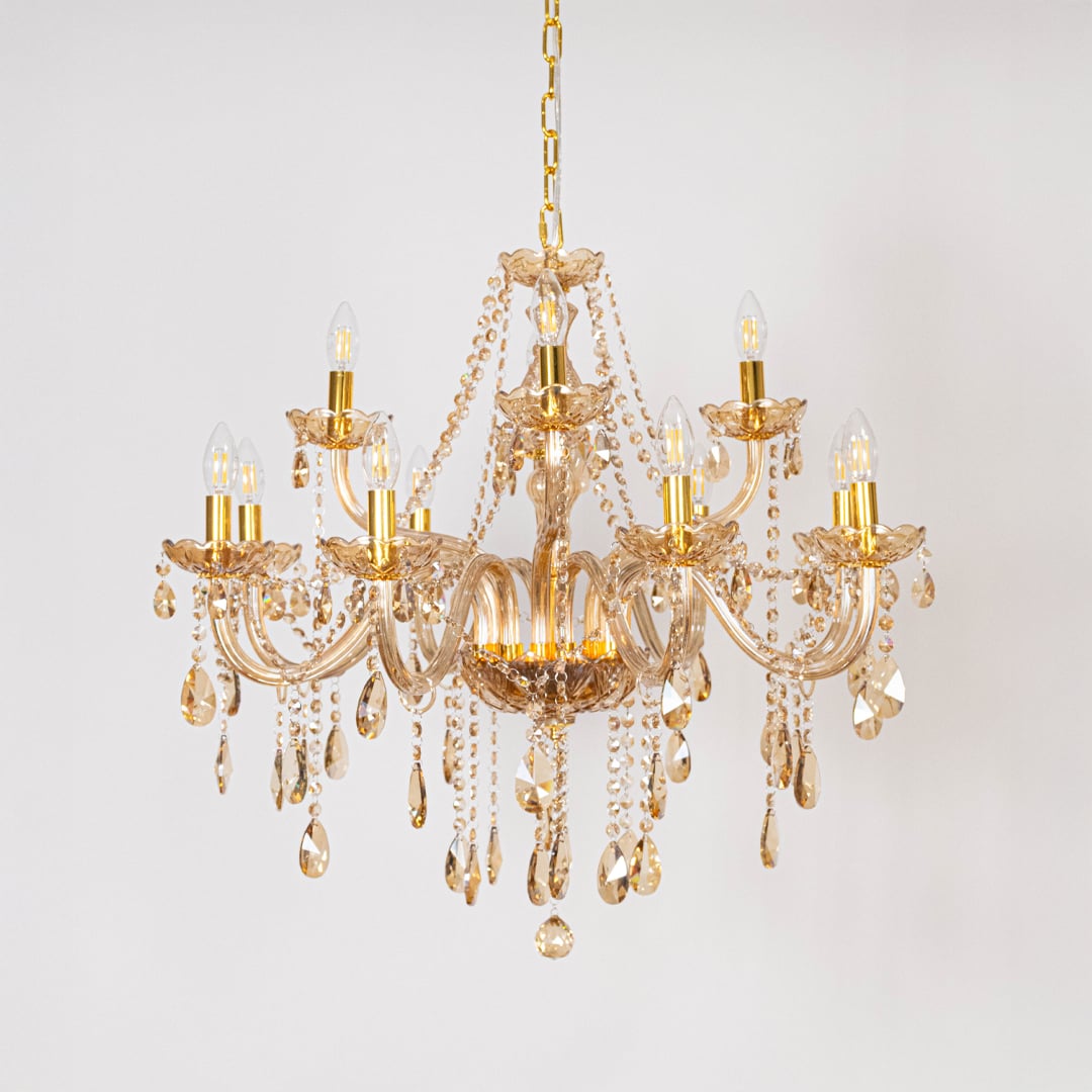 Golden chandelier with crystal droplets displayed off on white background for modern home interior lighting.