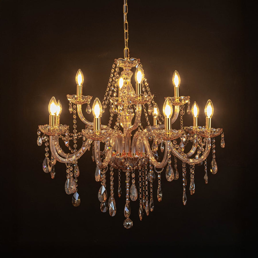 Golden chandelier with crystal detailing illuminated on black background for luxury home and hotel lighting.