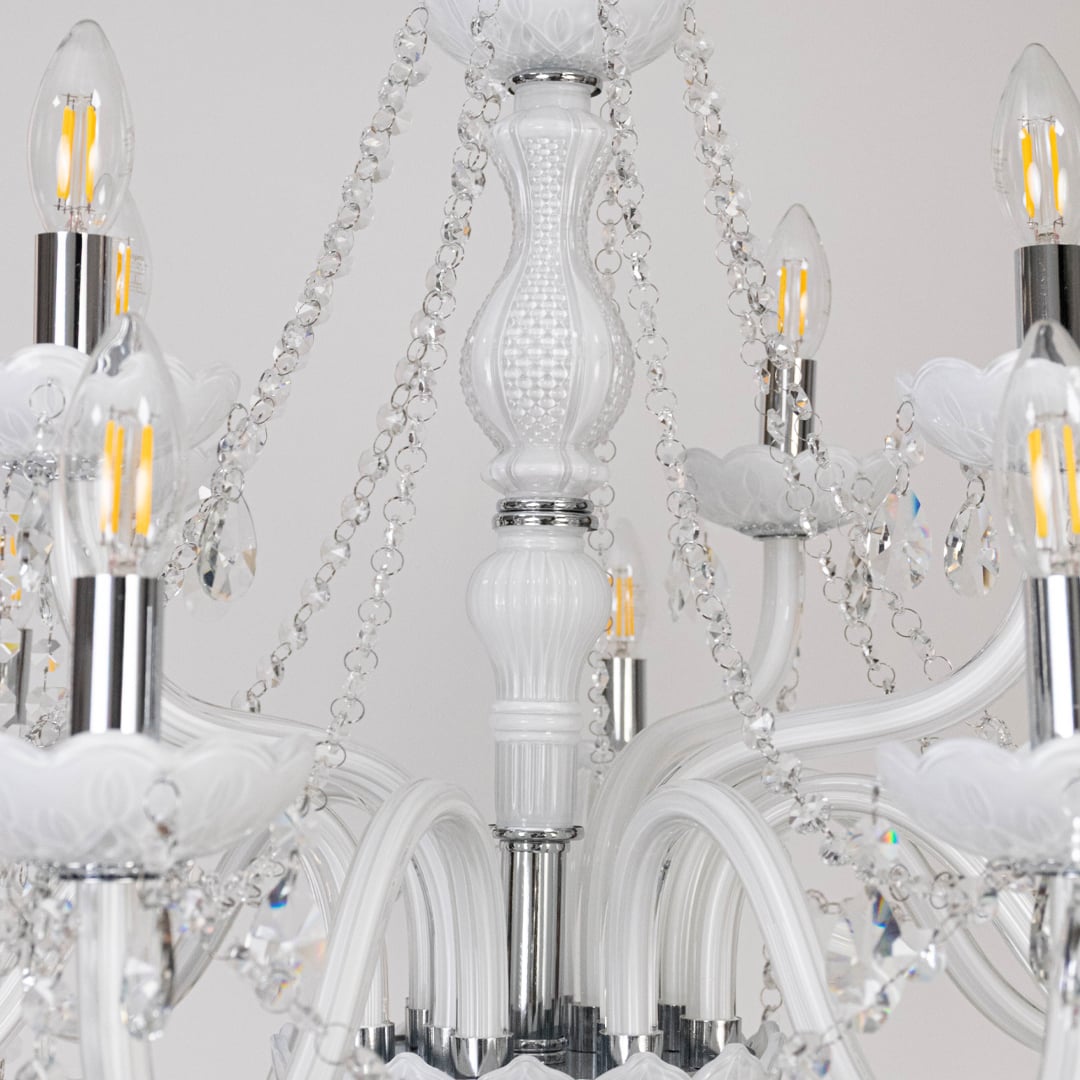 Closeup of white chandelier showing candle bulbs crystal beads and glass arms designed for luxury ceiling decor.