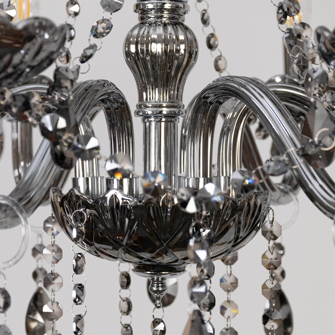 Closeup of chandelier with smoky grey frame and crystal droplets highlighting luxury decorative light design.