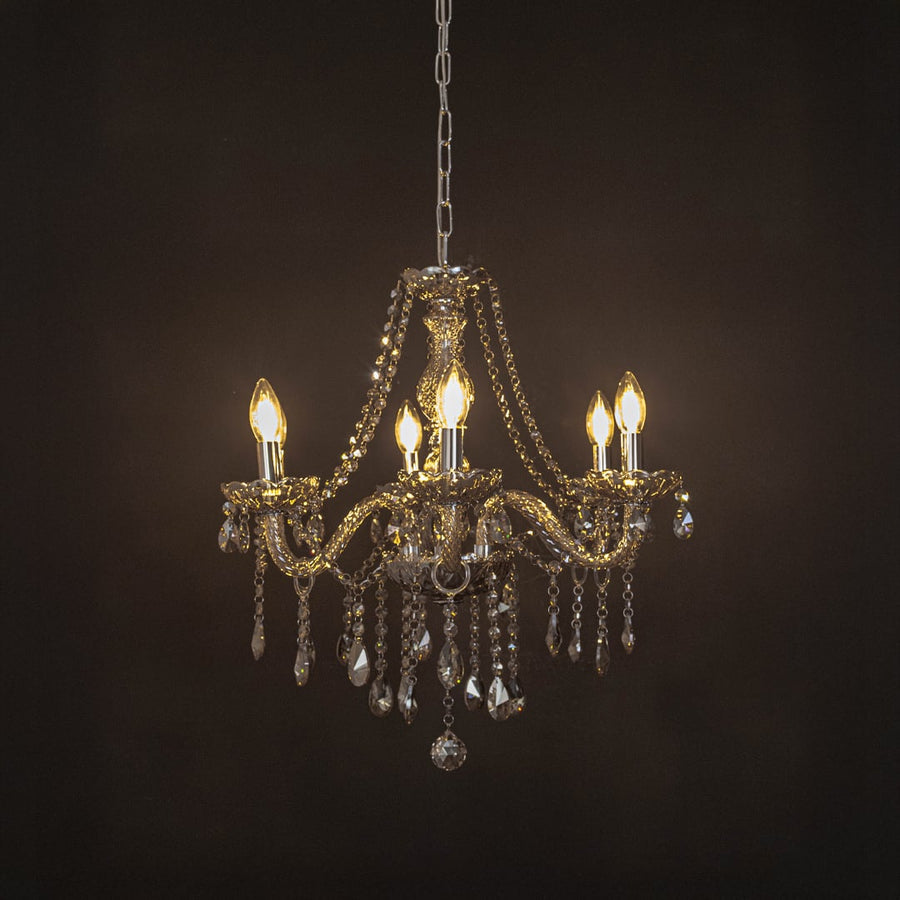 Elegant chandelier with golden crystal finish illuminated against black background for luxury home lighting.