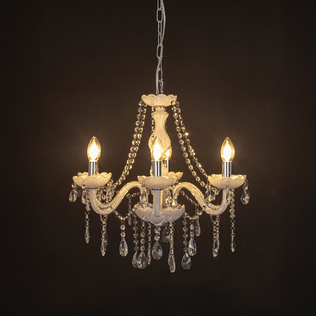 Elegant white chandelier with crystal accents illuminated against black background for modern decorative lighting.