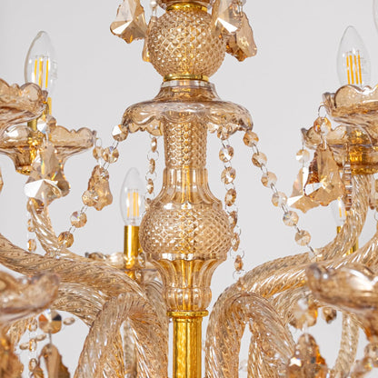 Closeup of golden chandelier showing crystal chains candle style bulbs and detailed glass body for home decor.
