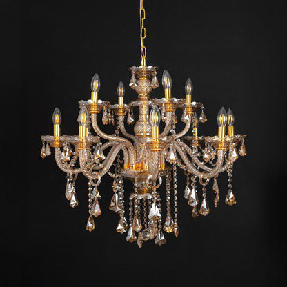 Golden chandelier with lights off highlighting crystal drops and glass arms against a black background.