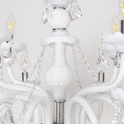 Closeup of white chandelier showing candle style bulbs crystal details and glass arms for luxury ceiling decor.