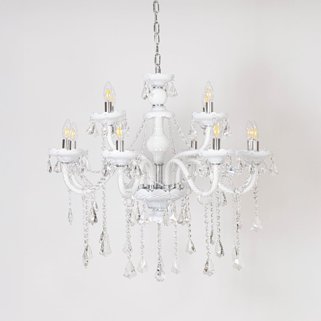 White chandelier with lights off showcasing crystal chains and glass arms photographed on plain white background.