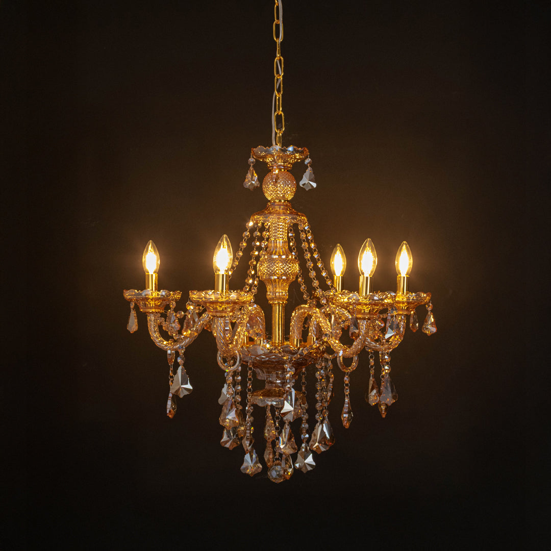 Gold crystal chandelier with radiant candle bulbs and shimmering crystal drops creating dramatic luxury interior lighting.
