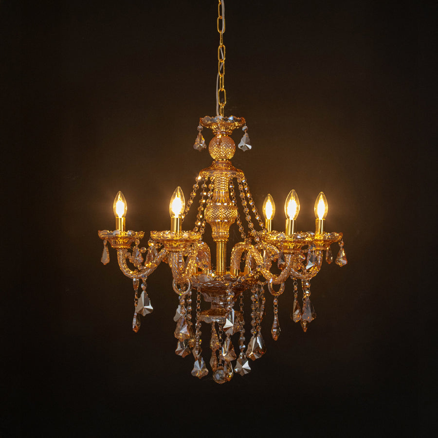 Gold crystal chandelier with radiant candle bulbs and shimmering crystal drops creating dramatic luxury interior lighting.