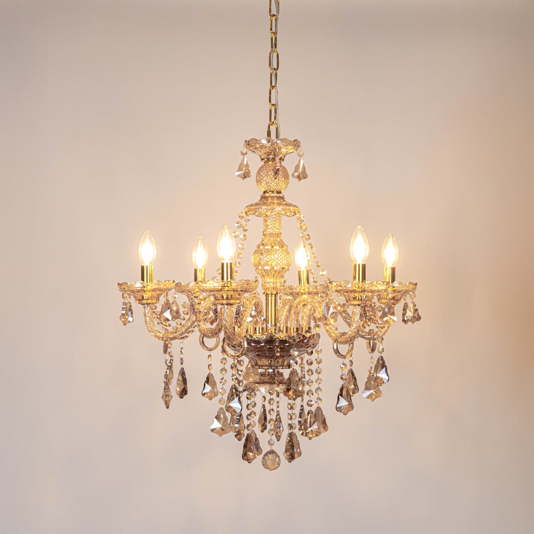 Crystal-chandelier ceiling light turned on with sparkling glow on white background.