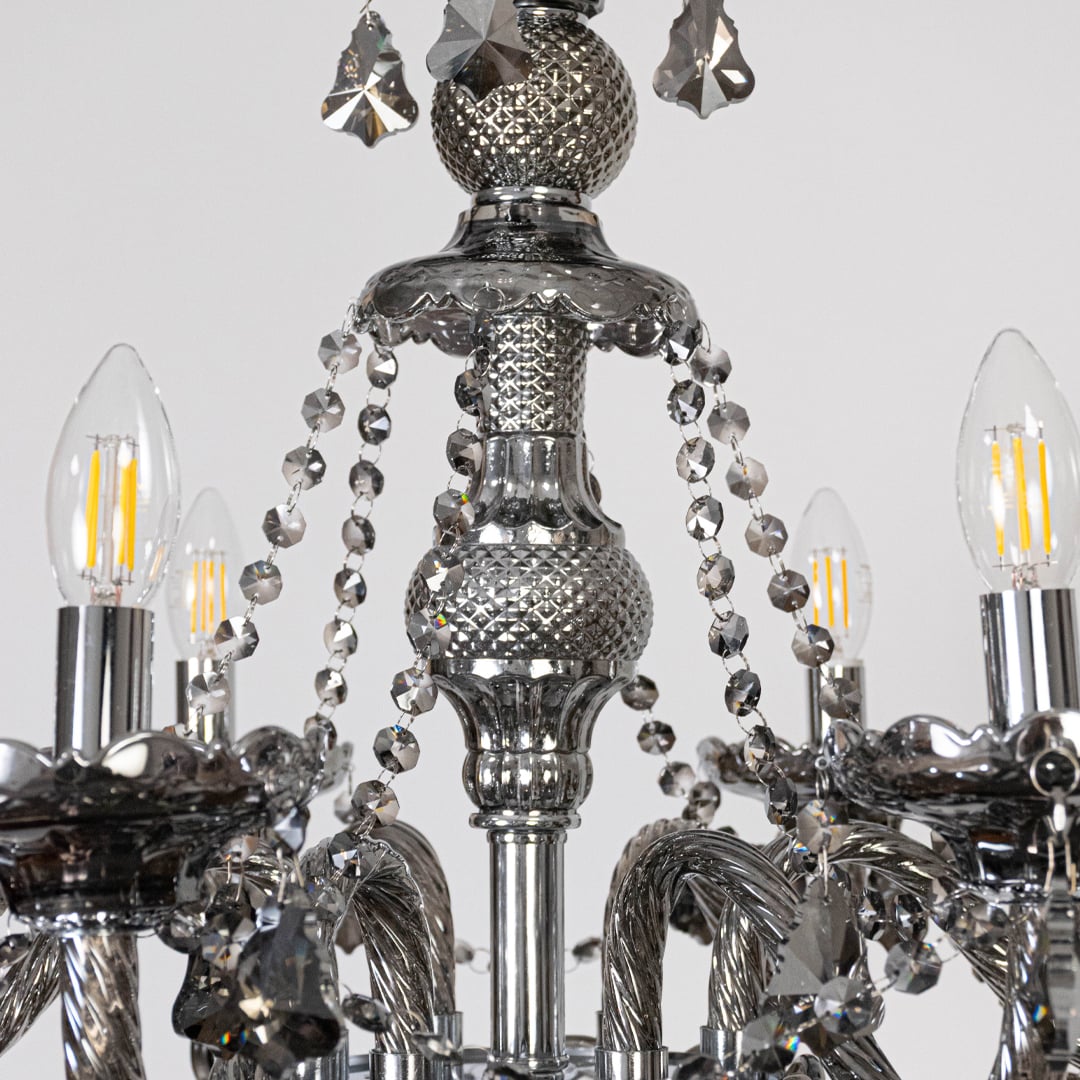 Closeup of chandelier with ornate arms and hanging crystal droplets for a luxurious finish.