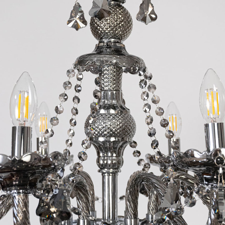 Closeup of chandelier with ornate arms and hanging crystal droplets for a luxurious finish.