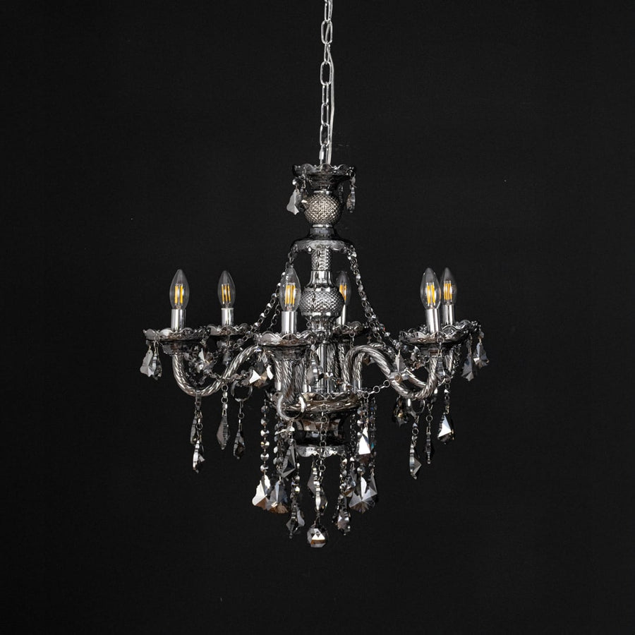 Chandelier displayed with lights off on black background showcasing crystal and metal details.