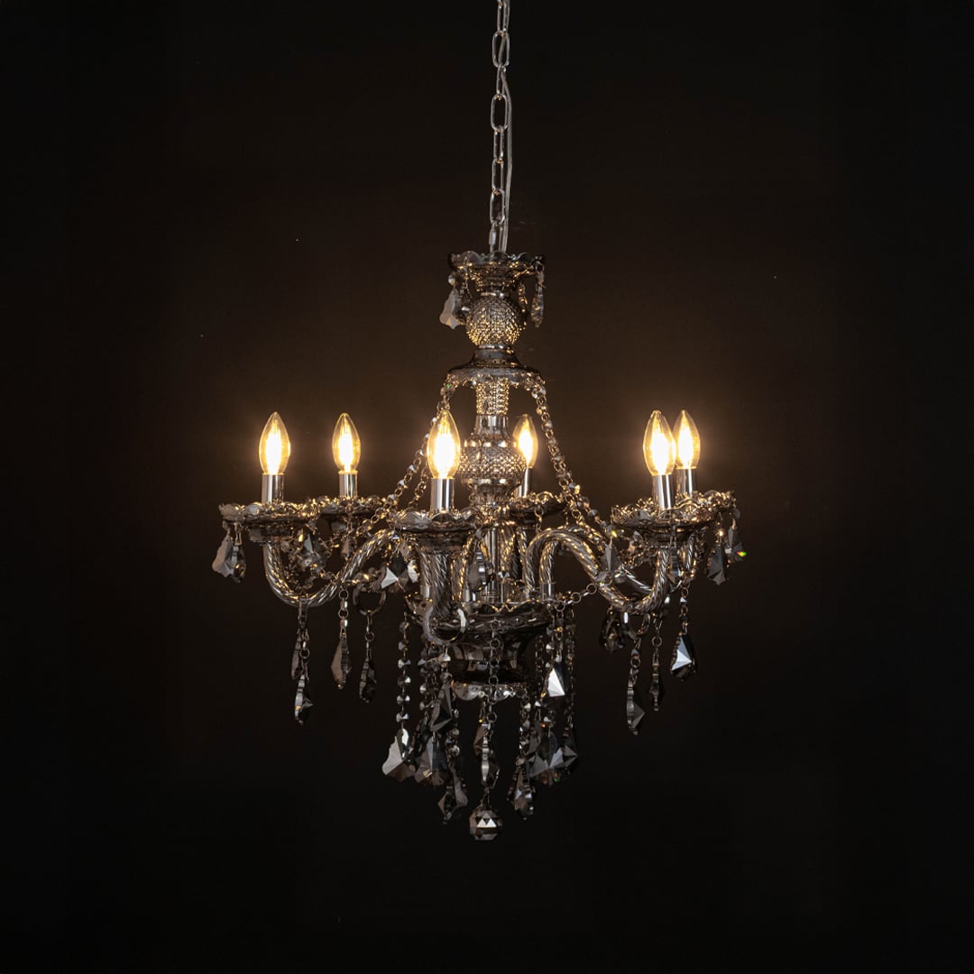 Chandelier illuminated with warm lights against a black background highlighting crystal design.