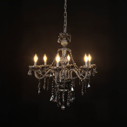 Chandelier illuminated with warm lights against a black background highlighting crystal design.