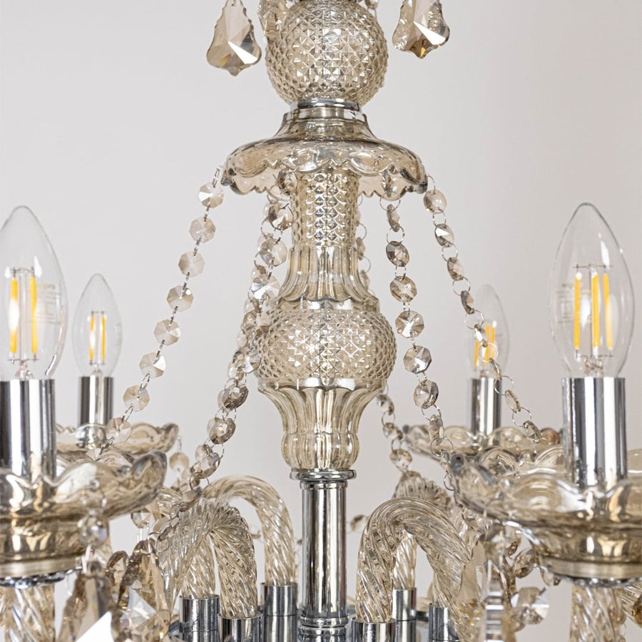 Closeup of golden chandelier with crystal detailing showing elegant carving and luxury lighting design.