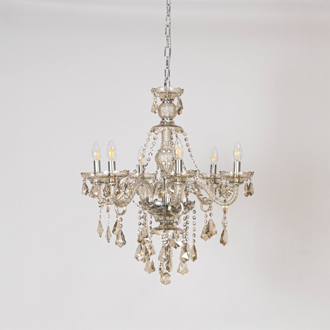 Golden chandelier with ornate crystal accents displayed off on white background for elegant lighting style.