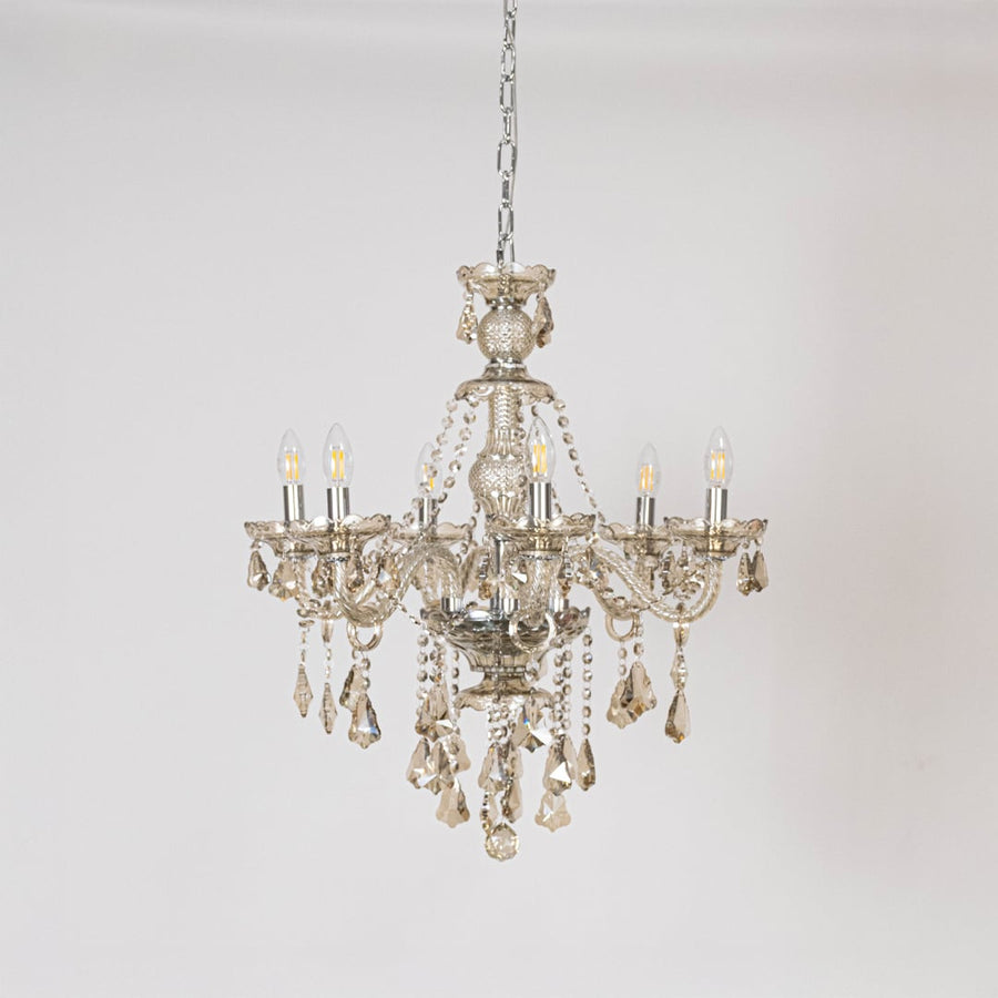 Golden chandelier with ornate crystal accents displayed off on white background for elegant lighting style.