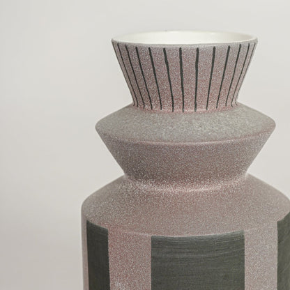 Closeup of handcrafted ceramic vase with ribbed neck and geometric color block design ideal for shelf or side table decor.