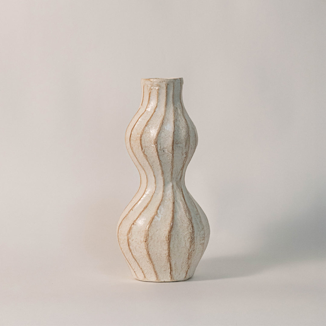 Beige ceramic decorative vase with sculpted wavy design for modern tabletop shelf and console decor placement.