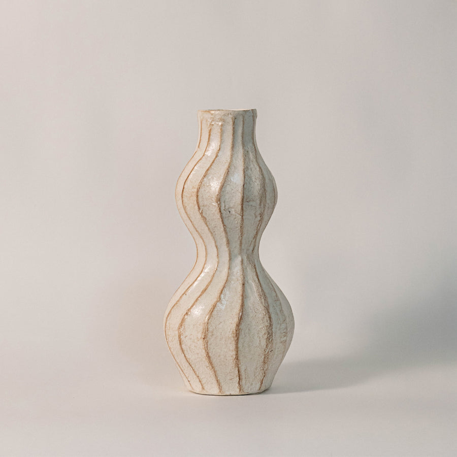 Beige ceramic decorative vase with sculpted wavy design for modern tabletop shelf and console decor placement.