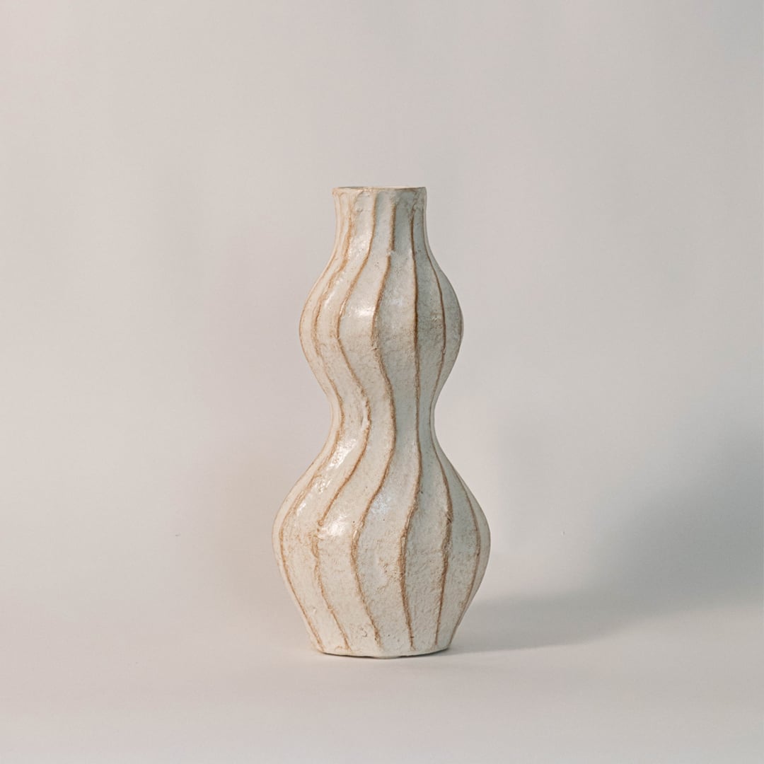 Wavy ceramic vase photographed on white background emphasizing its artistic sculptural design and textured surface.