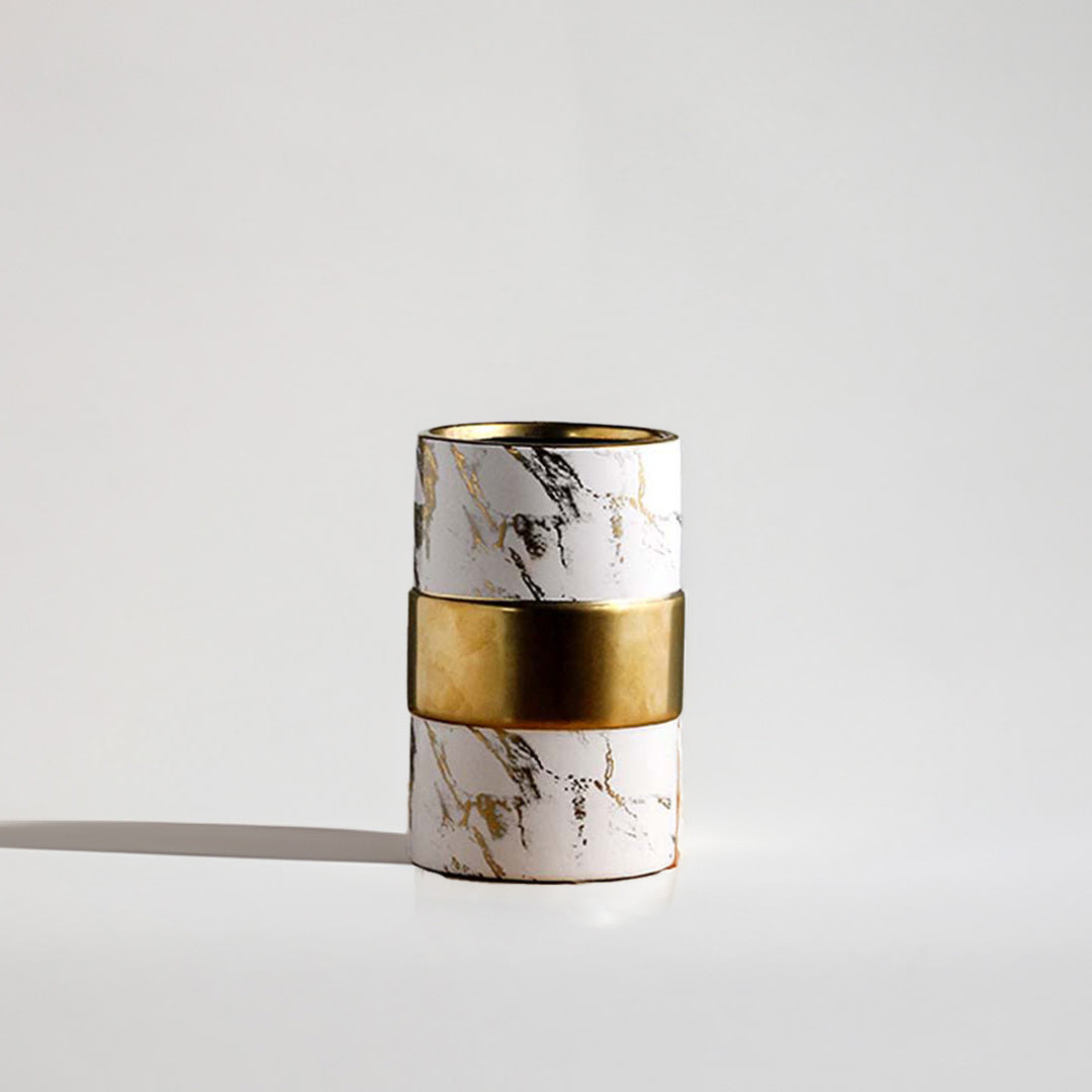 White ceramic cylinder vase featuring black and gold marble veins accented with a thick polished brass band in the center.