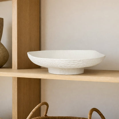 White ceramic pedestal fruit bowl with textured shell design for dining table centerpiece and modern kitchen decor display.