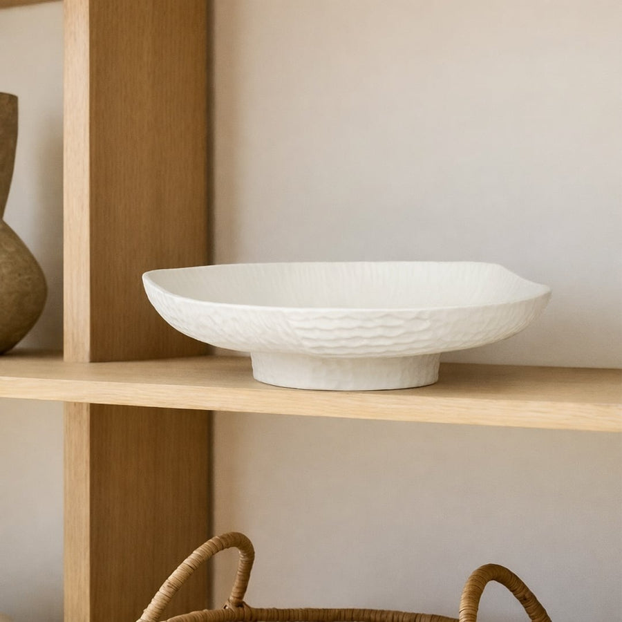 White ceramic pedestal fruit bowl with textured shell design for dining table centerpiece and modern kitchen decor display.