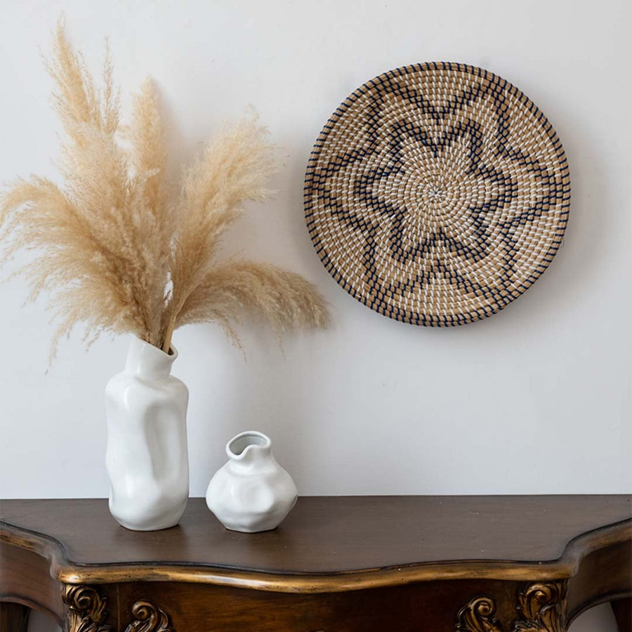 Handwoven wall basket decor in natural and black fiber with star pattern styled above console table.