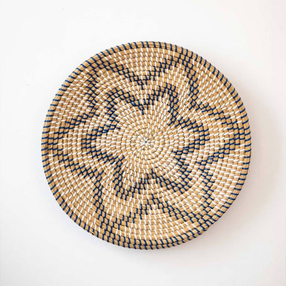 Beautiful star geometric patterned black and beige woven seagrass wall basket plate decoration isolated on white.
