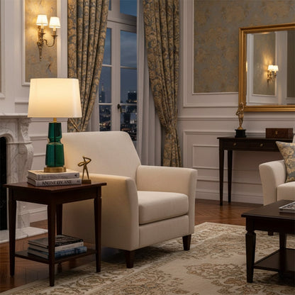Elegant living room with cream armchair green table lamp on wooden side table classic wall sconces patterned curtains and warm evening ambiance.