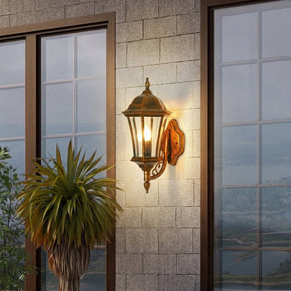 Vintage outdoor wall lantern with bronze metal frame and clear glass panels mounted beside door creating warm entrance lighting for exterior decor.