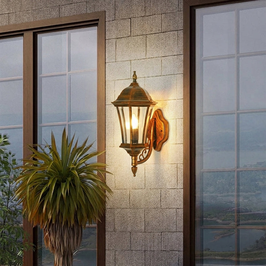 Vintage outdoor wall lantern with bronze metal frame and clear glass panels mounted beside door creating warm entrance lighting for exterior decor.