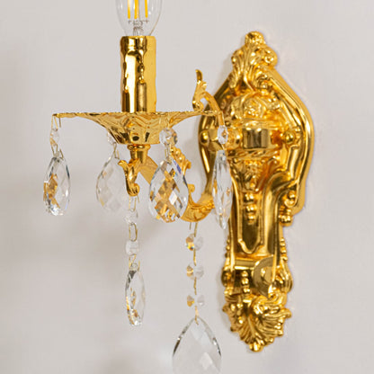 Closeup of golden wall light with crystal drops decorative candle style lighting for luxury home interiors.