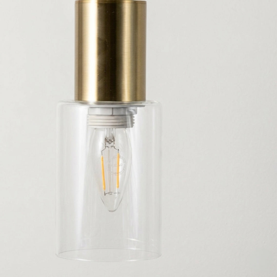 Elegant brass wall light with clear glass cylinder shade and sleek metallic finish for modern interiors.