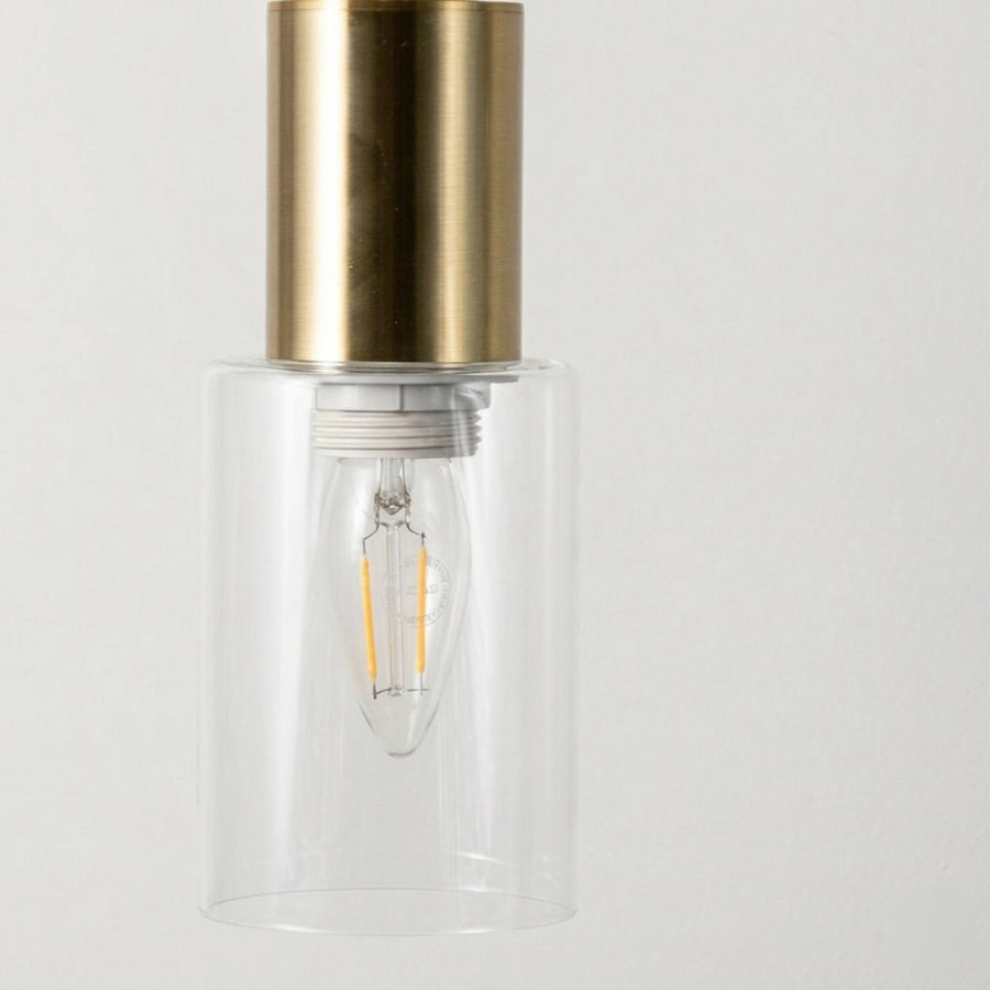 Elegant brass wall light with clear glass cylinder shade and sleek metallic finish for modern interiors.